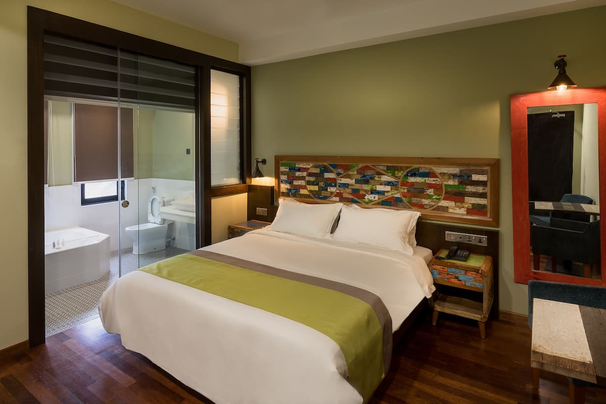 Ein Hotelzimmer mit Bett, Nachttisch, Lampe und Spiegel.