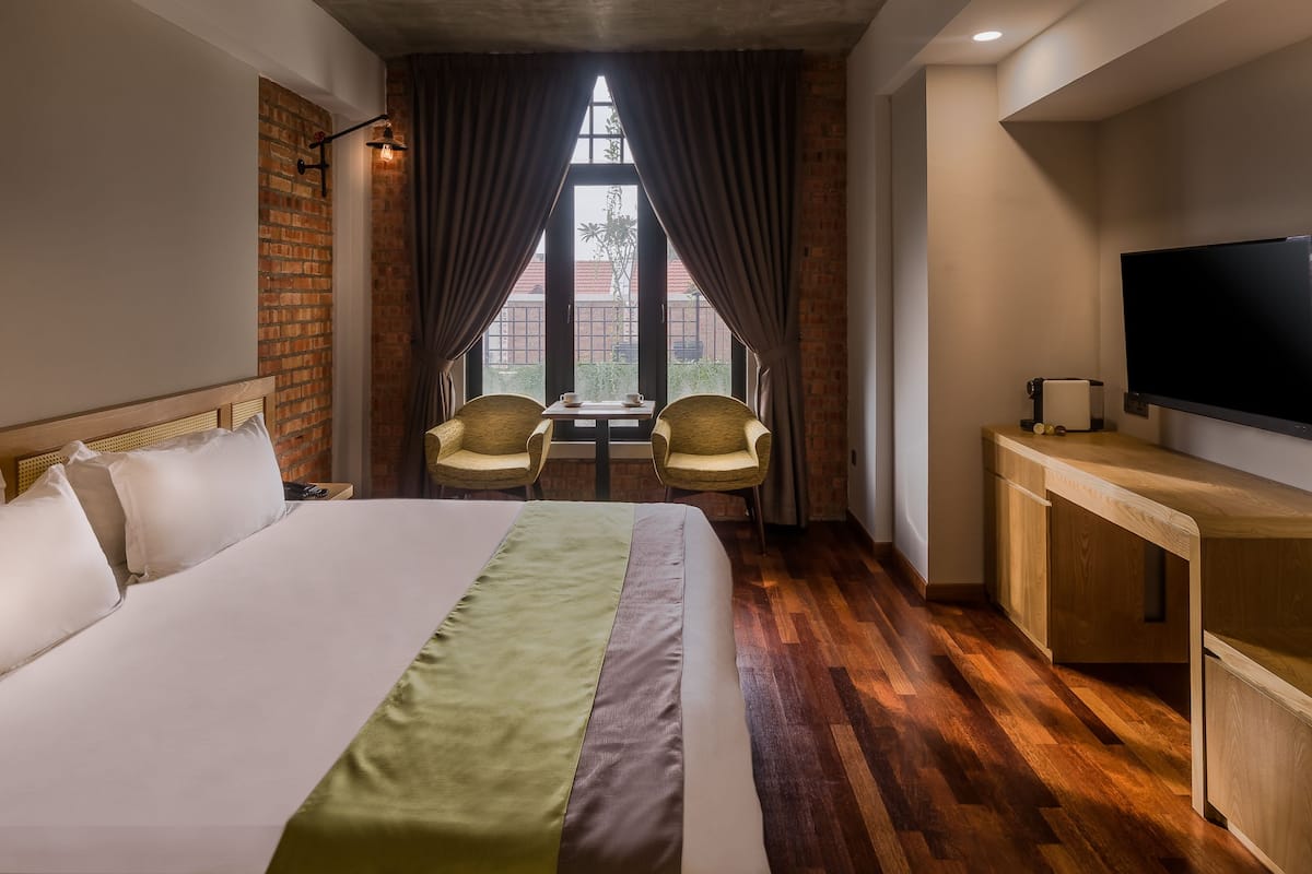 Ein Hotelzimmer mit Bett, Schreibtisch, Fernseher und Blick ins Freie durch ein Fenster.