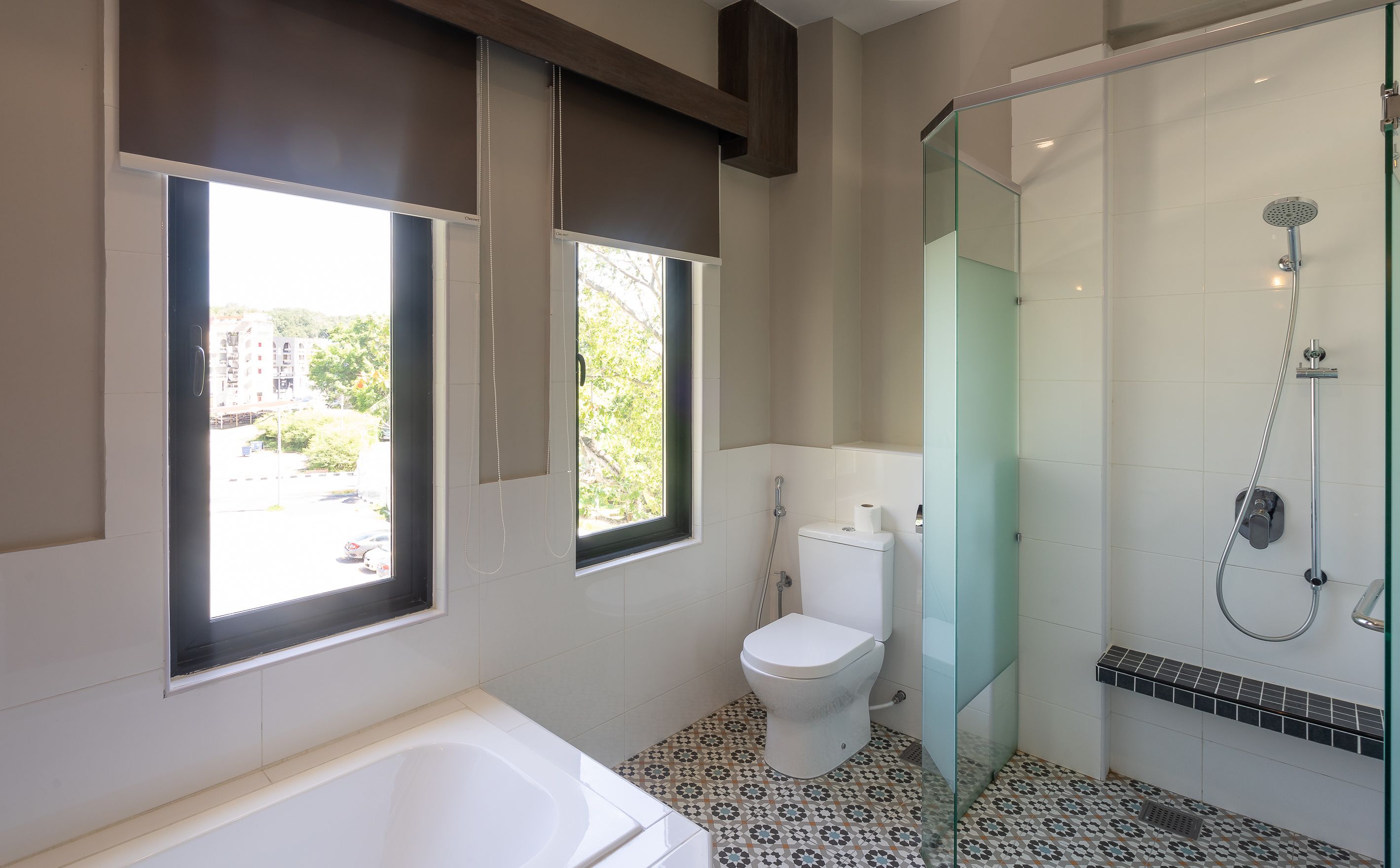 Een moderne badkamer met een douche met glazen wand, een bad en een toilet.