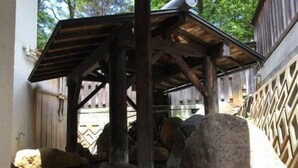 A rustic wooden structure with a sloped roof, surrounded by large rocks and a wooden fence. - Sanso Yunosato (Takayama)