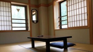 A tatami mat room with a low table and a cushion, large windows with shoji screens, and a mirror on the wall. - Sanso Yunosato (Takayama)