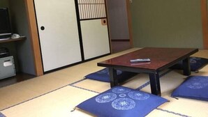 A traditional Japanese room with tatami flooring, a low table, cushions, and sliding doors. - Sanso Yunosato (Takayama)