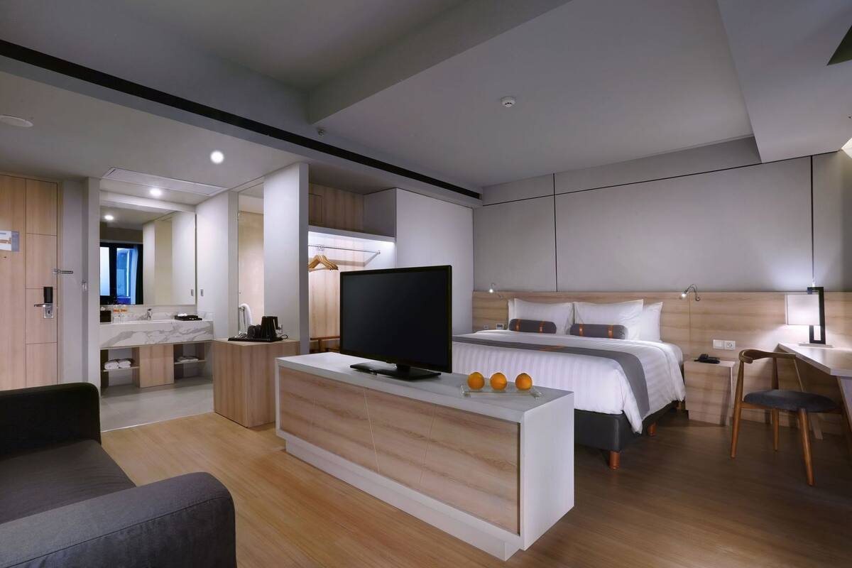 Una habitación de hotel moderna con cama, televisión, escritorio y zona de estar.