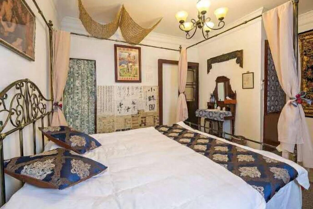Ein traditionell eingerichteter Raum mit einem großen Bett, einer Kandelaber und einem Spiegel.