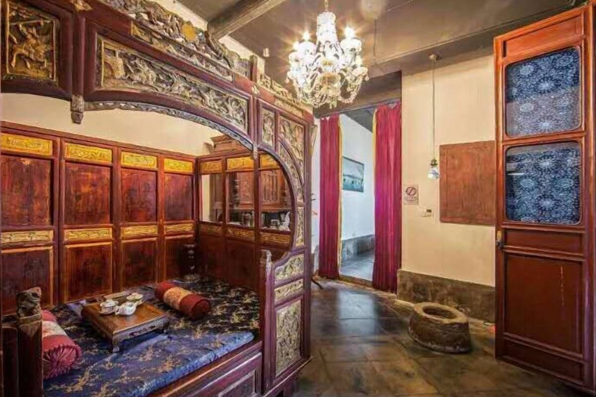 Ein traditionell eingerichteter Raum mit aufwendigen Holzmöbeln, einer Chandelüster und einem gemusterten Teppich.
