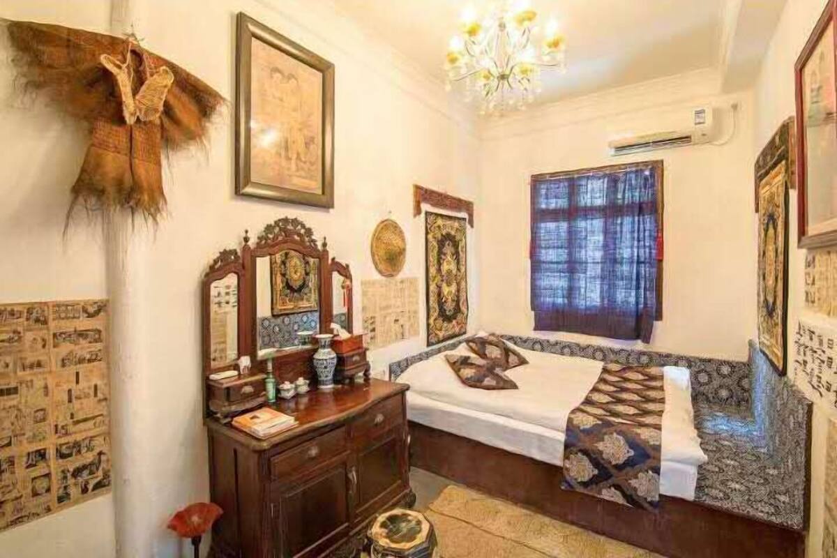 Ein traditionell eingerichteter Raum mit einem Bett, einer Holzkommode und einer Kristallleuchtre.