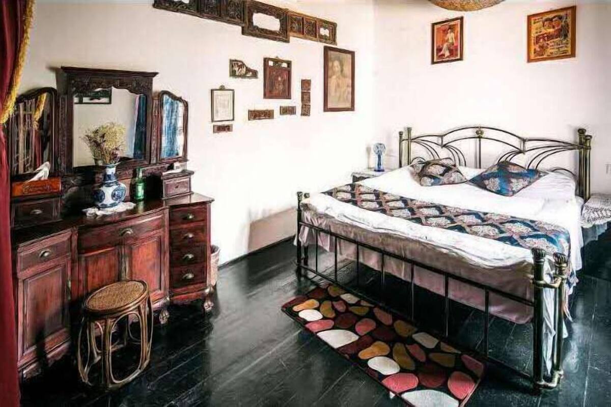 Ein Schlafzimmer mit Bett, Kommode und Wandspiegeln.
