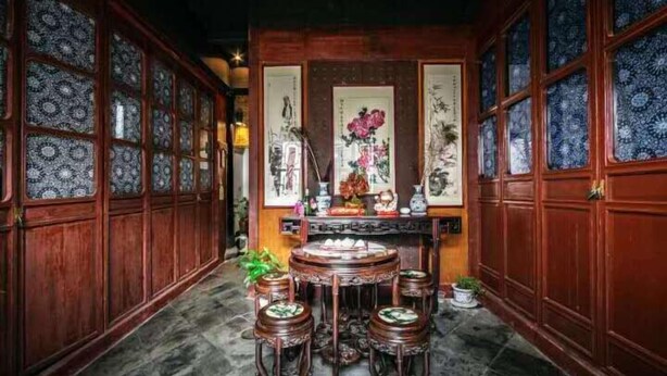Une pièce au décor traditionnel, avec des boiseries, une table ronde entourée de tabourets et une pièce décorative centrale.