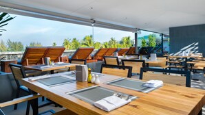 A restaurant with wooden tables and chairs, some with umbrellas. - Kamala Resotel (Kamala)