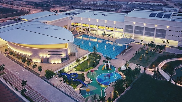 A hotel with a large swimming pool, a children's play area, and a modern building with a curved roof. - Salam Homestay d'Sendayan (Bandar Sri Sendayan)