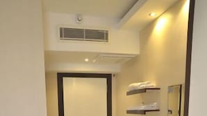 A hotel room with a bed, a small desk with a mirror, a radiator, and a door leading to another room. - Kayislioglu Hotel (Burdur)