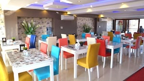 A dining area with multiple tables and chairs, air conditioning units, and potted plants. - Kayislioglu Hotel (Burdur)