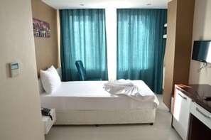Une chambre d’hôtel avec un lit, un bureau, une chaise et un téléviseur.