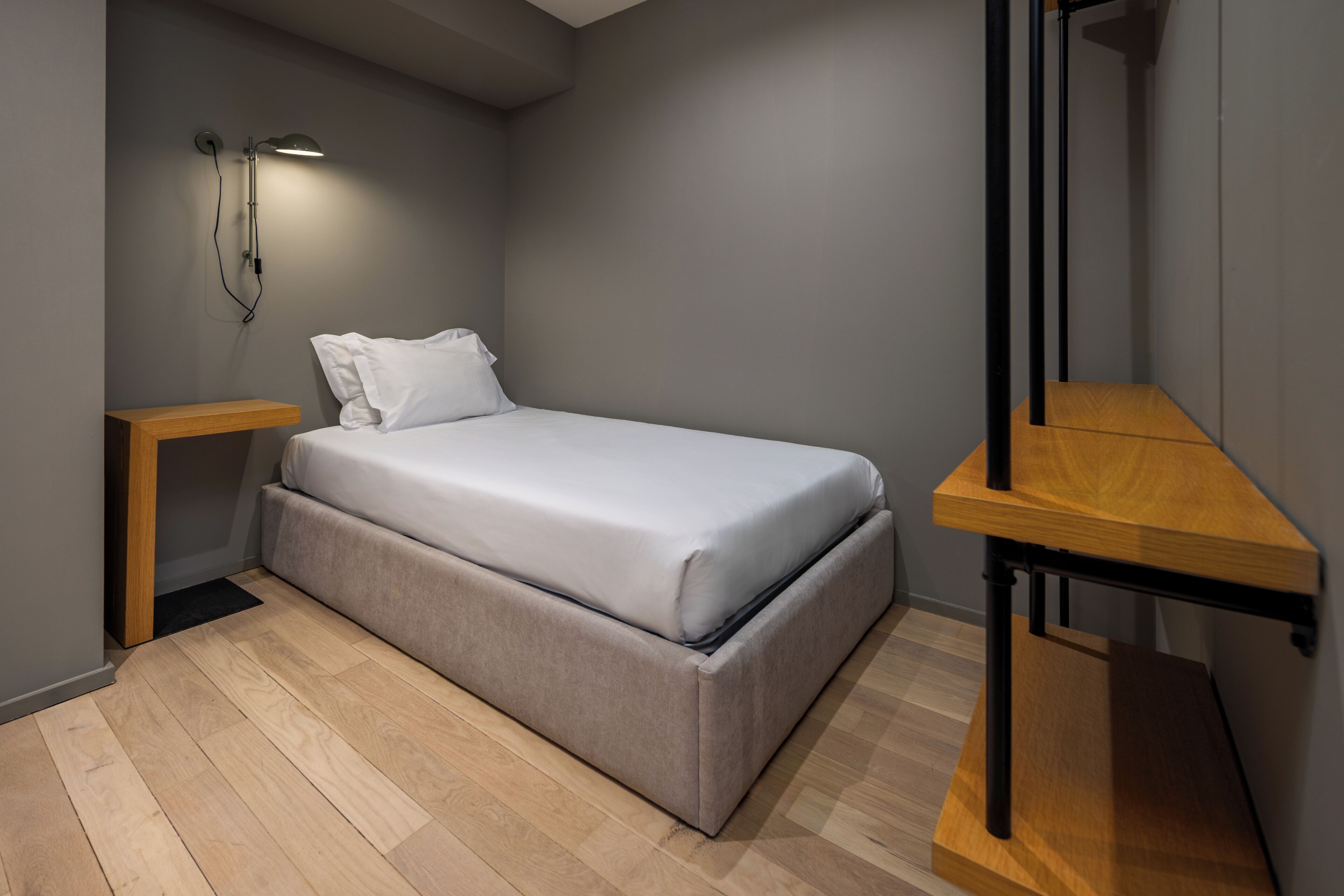 Un dormitorio moderno con cama, mesitas de noche, una mesita auxiliar y un banco de madera.