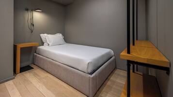 Un dormitorio moderno con cama, mesitas de noche, una mesita auxiliar y un banco de madera.