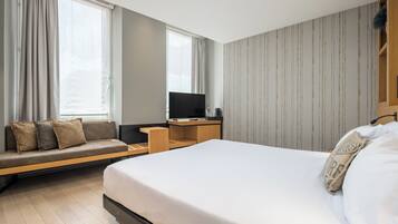 Een moderne hotelkamer met een groot bed, een bank, een bureau en een televisie.