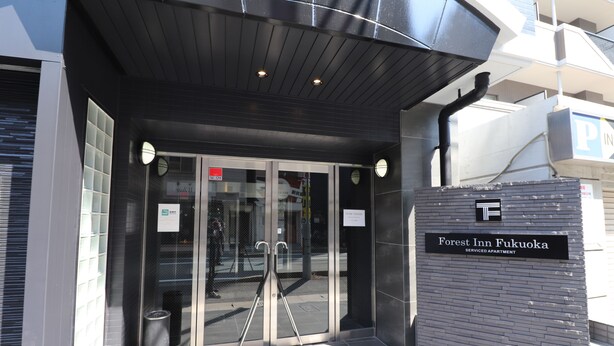 The entrance to the Forest Inn Fukuoka serviced apartment with a modern design, including a glass door entrance and a signboard. - Forest Inn Fukuoka (Fukuoka)
