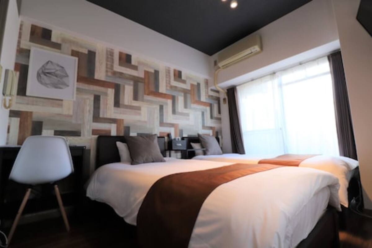 A modern hotel room with a large bed, a desk, and a chair.