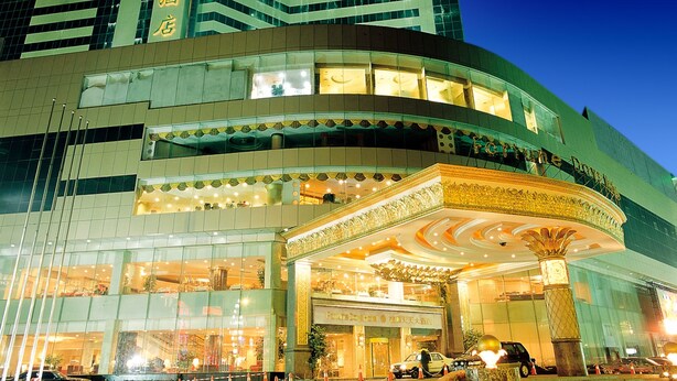 Un hôtel à plusieurs étages, doté d’une façade incurvée, de grandes fenêtres en verre et d’une entrée imposante agrémentée d’éléments décoratifs.