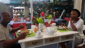 A dining table with a Buddha statue, a vase with green leaves, and a teapot. - Mitchells Guesthouse (Cape Town)