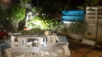 Maqueta de un edificio con un jardín central, rodeado de diversas plantas y una estructura azul al fondo.