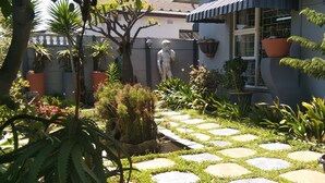 A garden with a stone pathway, potted plants, and a statue. - Mitchells Guesthouse (Cape Town)