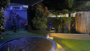 A well-lit outdoor area with a water feature, exercise equipment, and various plants. - Mitchells Guesthouse (Cape Town)
