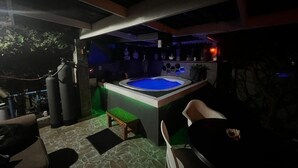 An outdoor hot tub area with seating and a stone floor. - Mitchells Guesthouse (Cape Town)