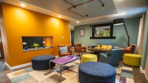 A modern living room with a sofa, ottomans, and a coffee table. - Jonas Hotel (Sheffield)