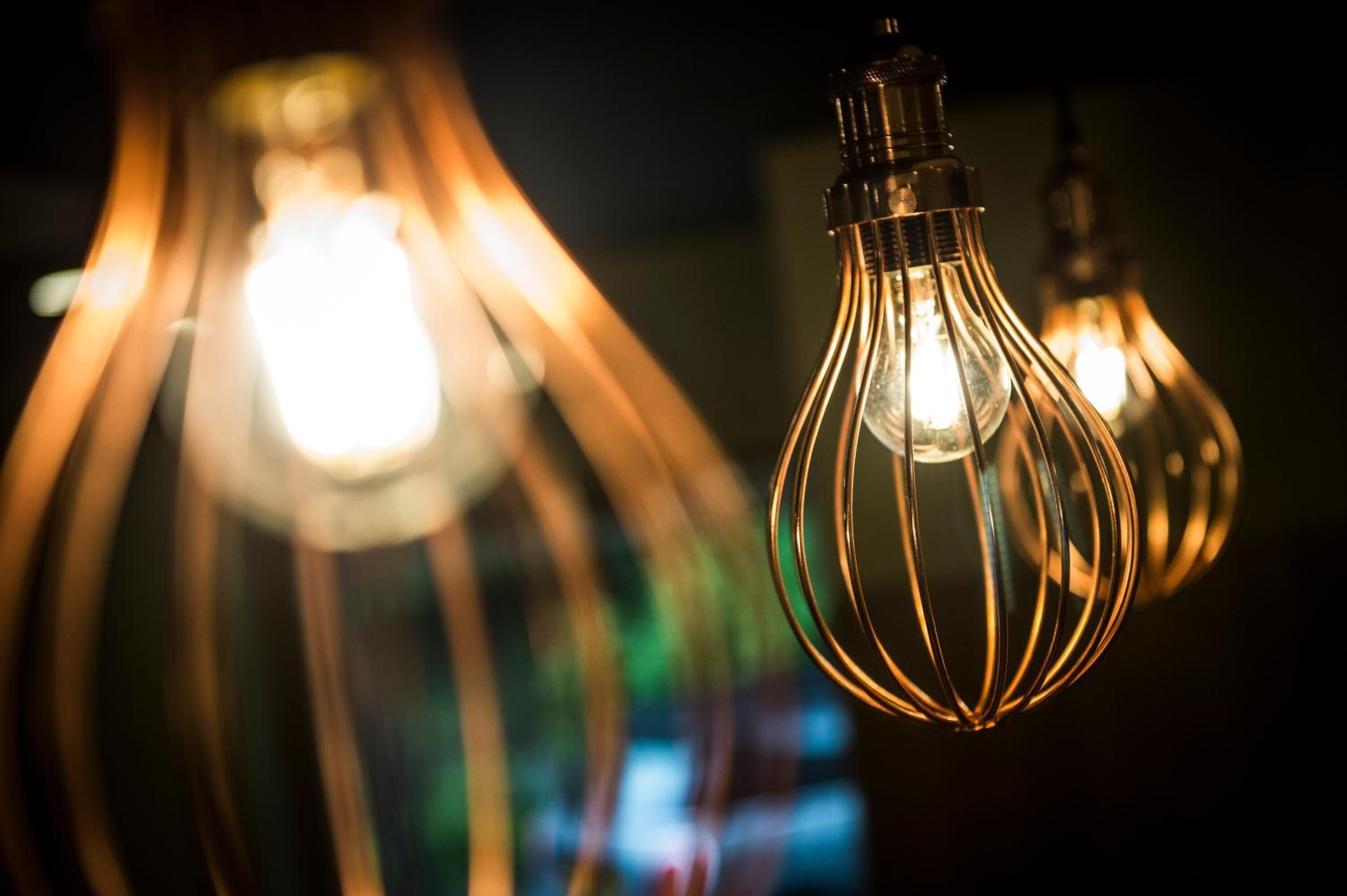 Un gros plan d’un luminaire doté d’une ampoule en verre et de câbles métalliques.