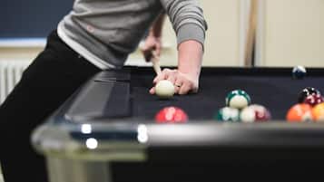 A person playing pool, focusing on the cue stick and balls on the table.