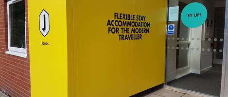 Ein gelbes Unterkunftsmodul mit einem Schild, auf dem steht: 'Flexible Stay Accommodation for the Modern Traveller.'