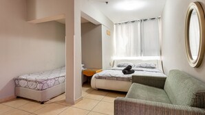 Un dormitorio con dos camas, un sofá, una mesita y un espejo.