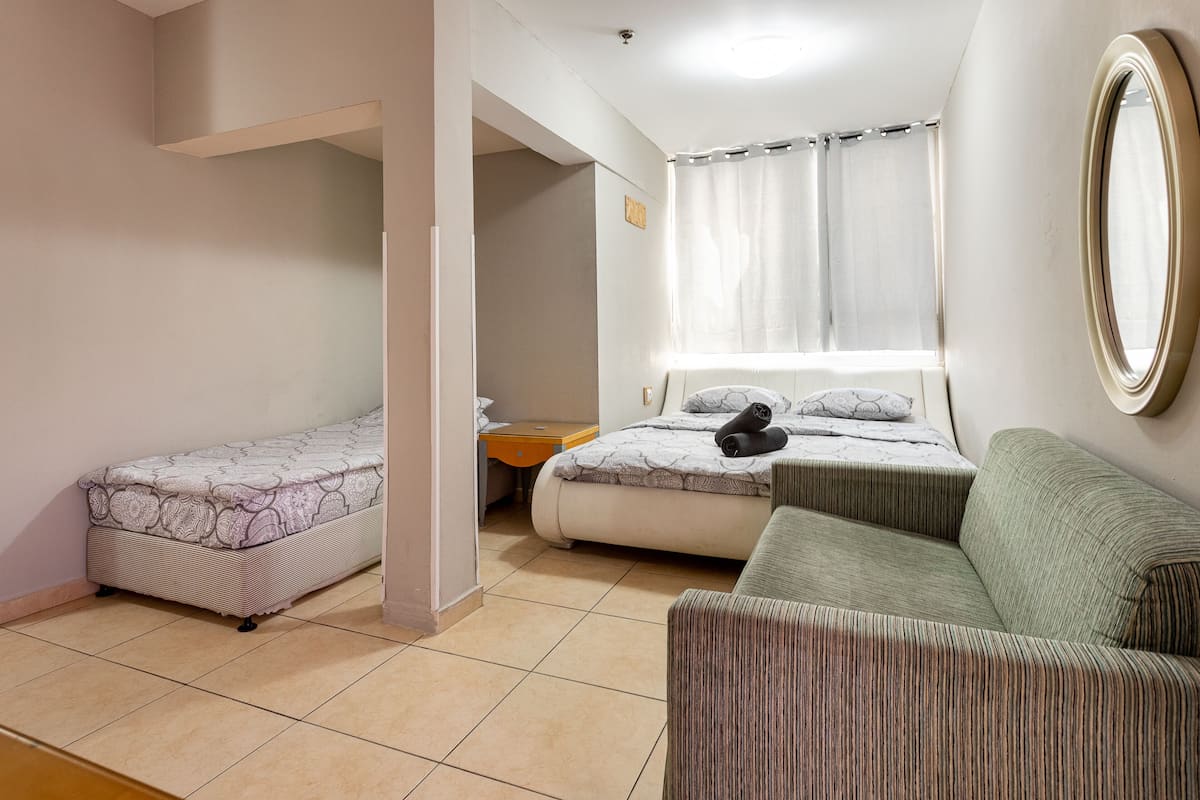 Un dormitorio con dos camas, un sofá, una mesita y un espejo.