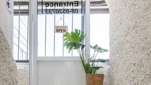 Una puerta con un cartel que dice 'Welcome', un felpudo que dice 'Home Sweet Home' y una planta en maceta sobre un taburete.