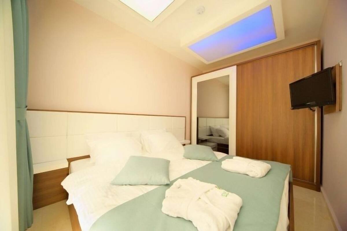 Une chambre d’hôtel avec un lit, un téléviseur fixé au mur et une lucarne au-dessus du lit.