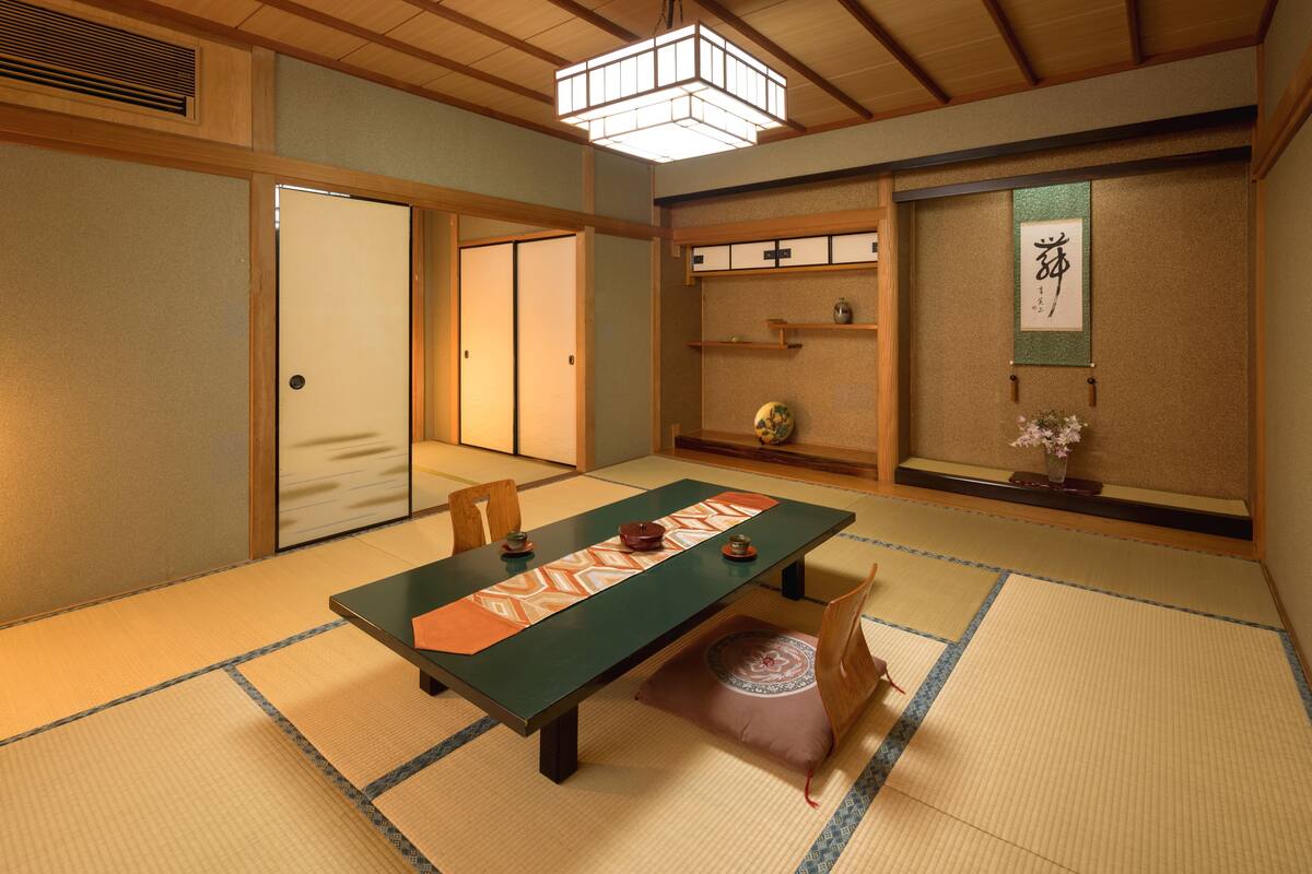 A traditional Japanese room with tatami flooring, a low table, and sliding doors.