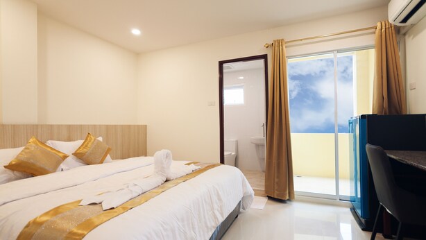 Une chambre d’hôtel moderne, dotée d’un grand lit, d’un bureau et offrant une vue sur le ciel par les portes du balcon.