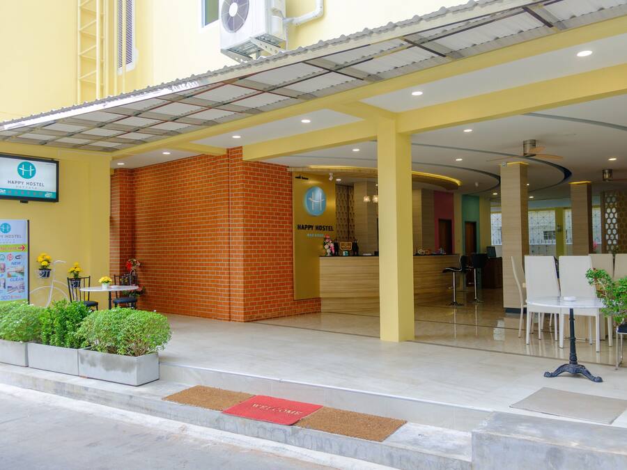 A hostel entrance with a reception desk, seating area, and a sign indicating hostel services.