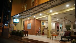 Une auberge de jeunesse avec une façade en briques, un comptoir d’accueil et un espace détente avec des chaises et des tables.