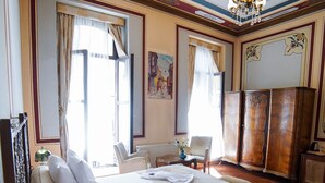 Une chambre d’hôtel avec un grand lit, un lustre, une armoire en bois et une vue sur l’extérieur.