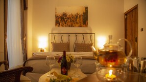 Une chambre d’hôtel avec un lit, une table de chevet sur laquelle se trouvent une bouteille de vin, des verres et une bougie.