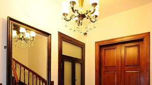 Un escalier en bois, avec une chaise et une petite table, dans un couloir éclairé par un lustre.