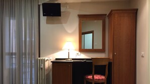 A small, well-lit room with a desk, chair, and a cabinet. - Hotel Excelsior (Pavia)