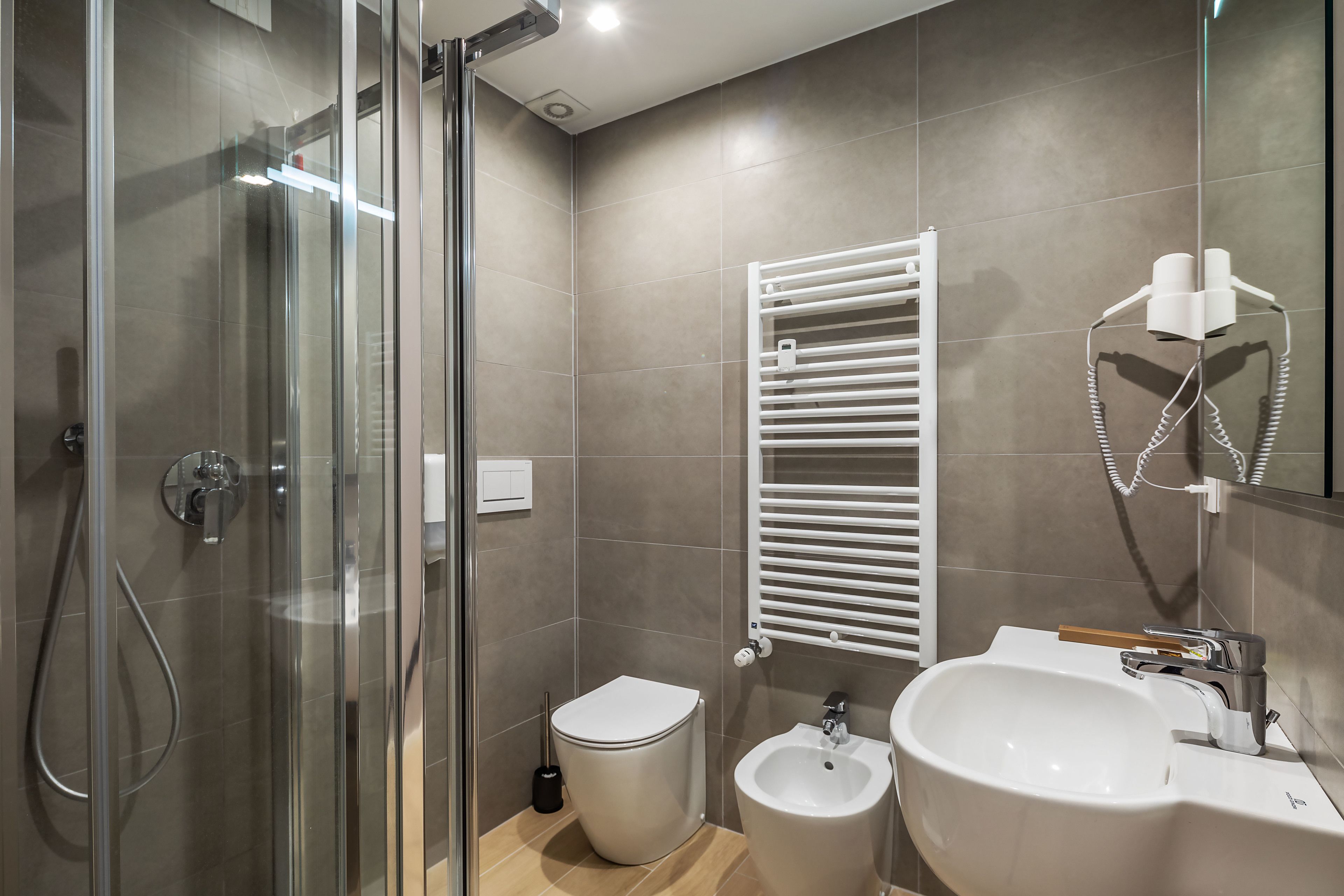 A modern bathroom with a glass shower enclosure, a white toilet, a bidet, and a sink with a mirror.