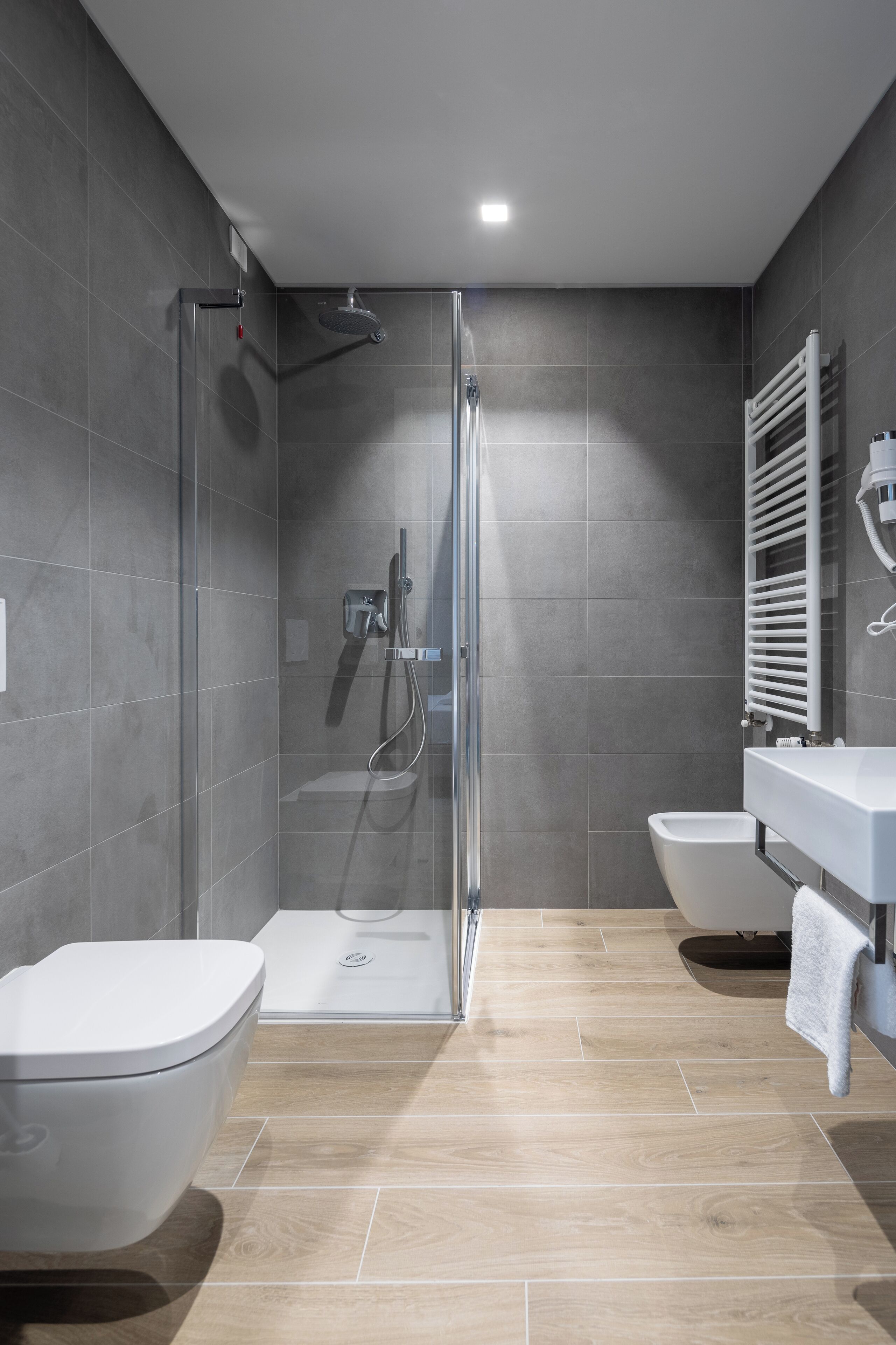 A modern bathroom with a glass-enclosed shower, a freestanding bathtub, and a white sink.