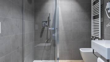 A modern bathroom with a glass-enclosed shower, a freestanding bathtub, and a white sink.