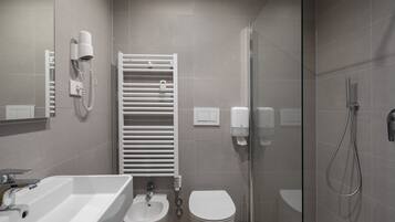 Ein modernes Badezimmer mit Waschbecken, Bidet, Toilette, Handtuchhalter und einer Duschkabine.
