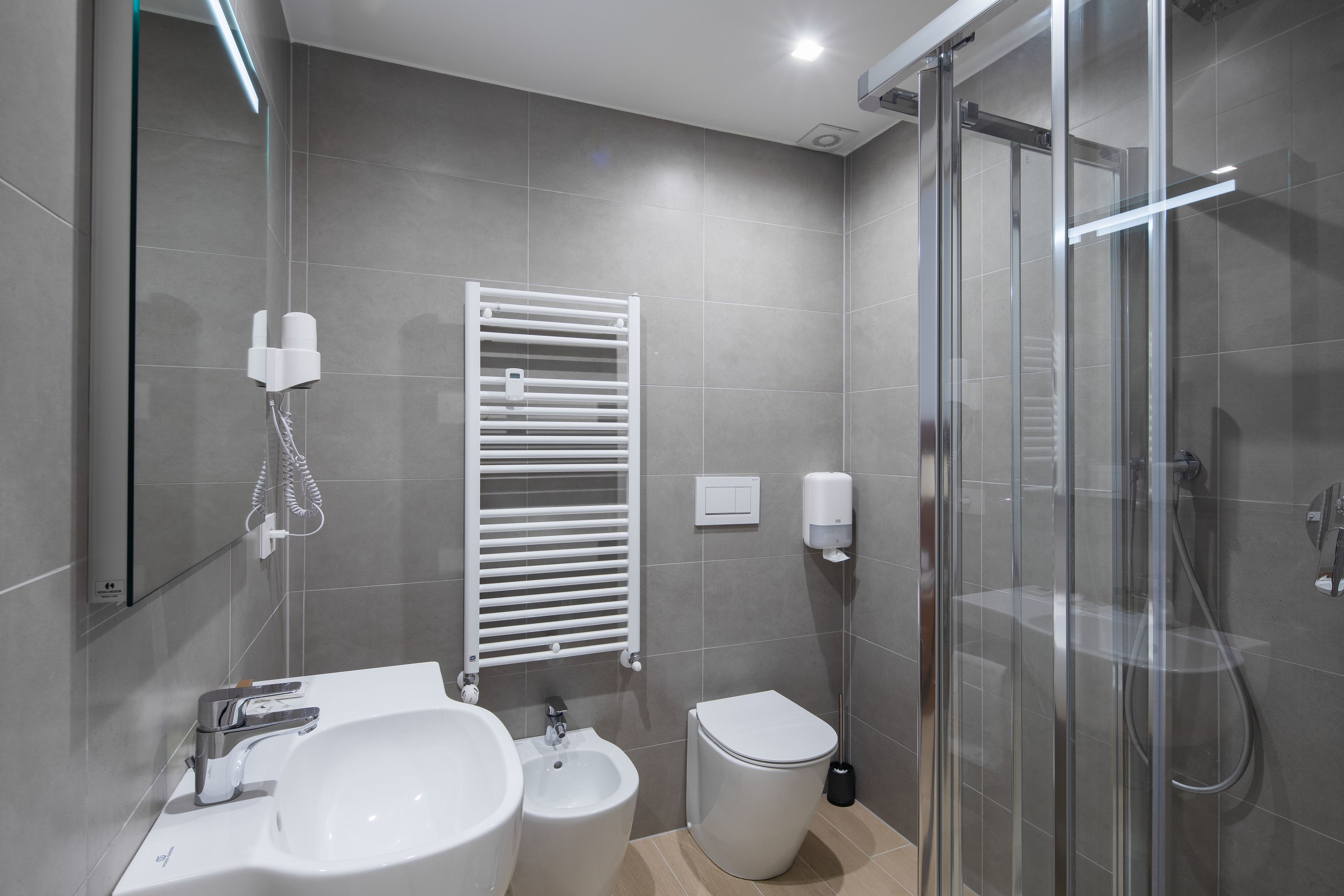 Un baño moderno con lavamanos, bidé, inodoro y cabina de ducha de vidrio.