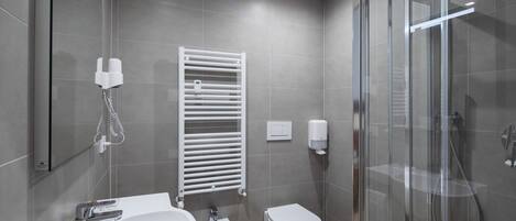 Un baño moderno con lavamanos, bidé, inodoro y cabina de ducha de vidrio.